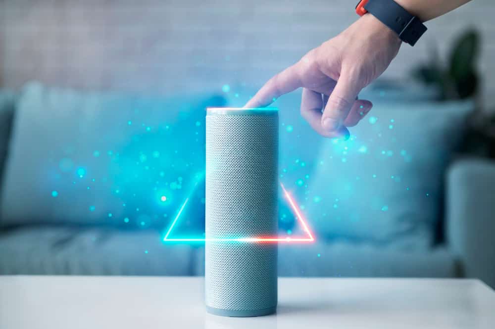 An individual is pointing at an Alexa smart speaker, showcasing the advanced voice recognition technology.